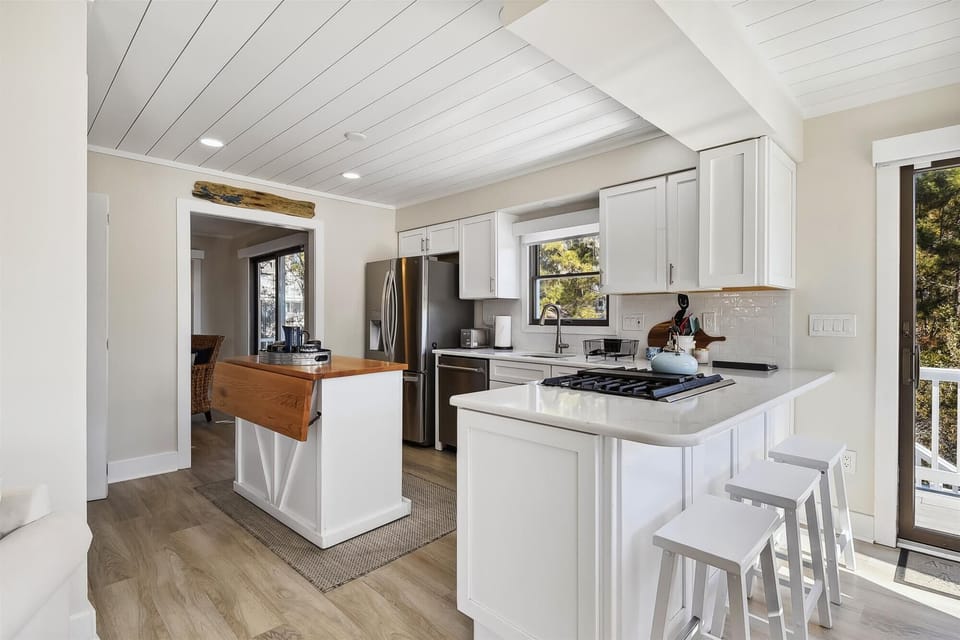 Your bright, modern kitchen features stainless steel appliances, a gas cooktop, and cozy breakfast bar seating—perfect for preparing meals and enjoying leisurely mornings with coffee while sunlight streams through the windows.