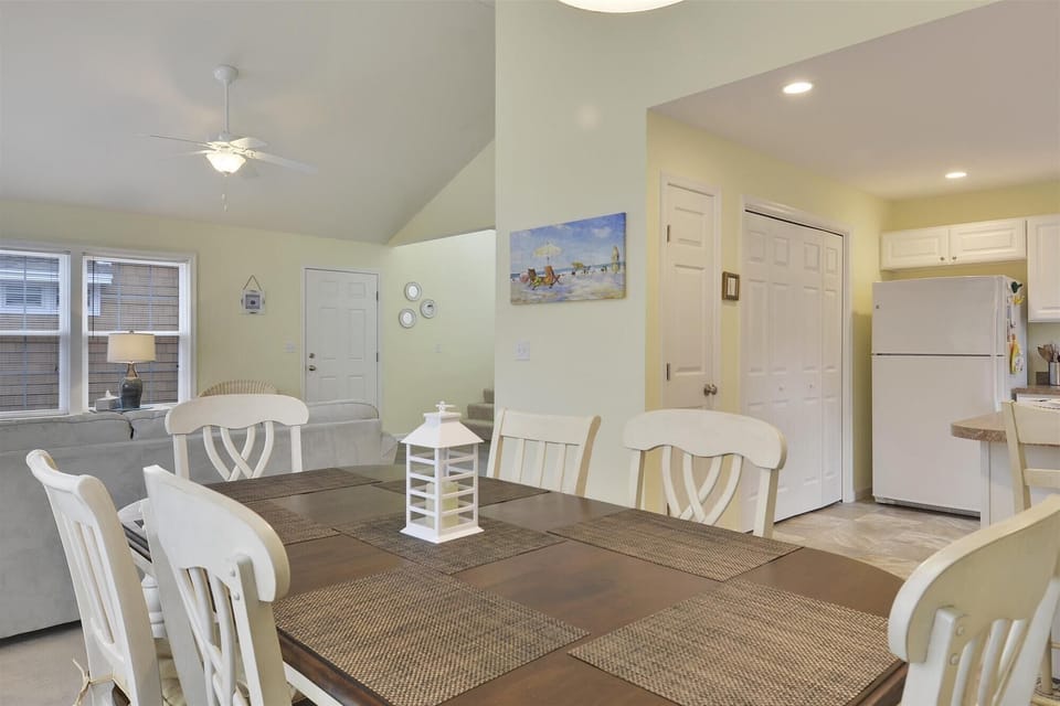 Your bright coastal retreat blends comfort and charm with soft hues, beach-themed art, and an open layout connecting the dining area, living room, and kitchen—perfect for relaxing meals and lazy evenings.