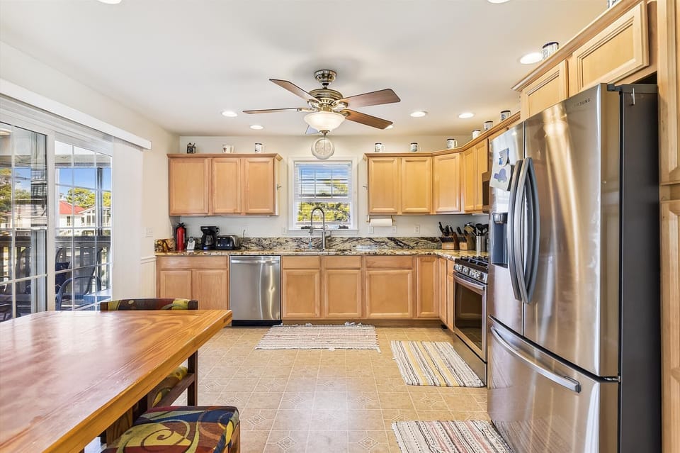 Your spacious, well-equipped kitchen invites you to prepare memorable meals with stainless steel appliances, granite countertops, and warm natural light streaming through windows overlooking the neighborhood.