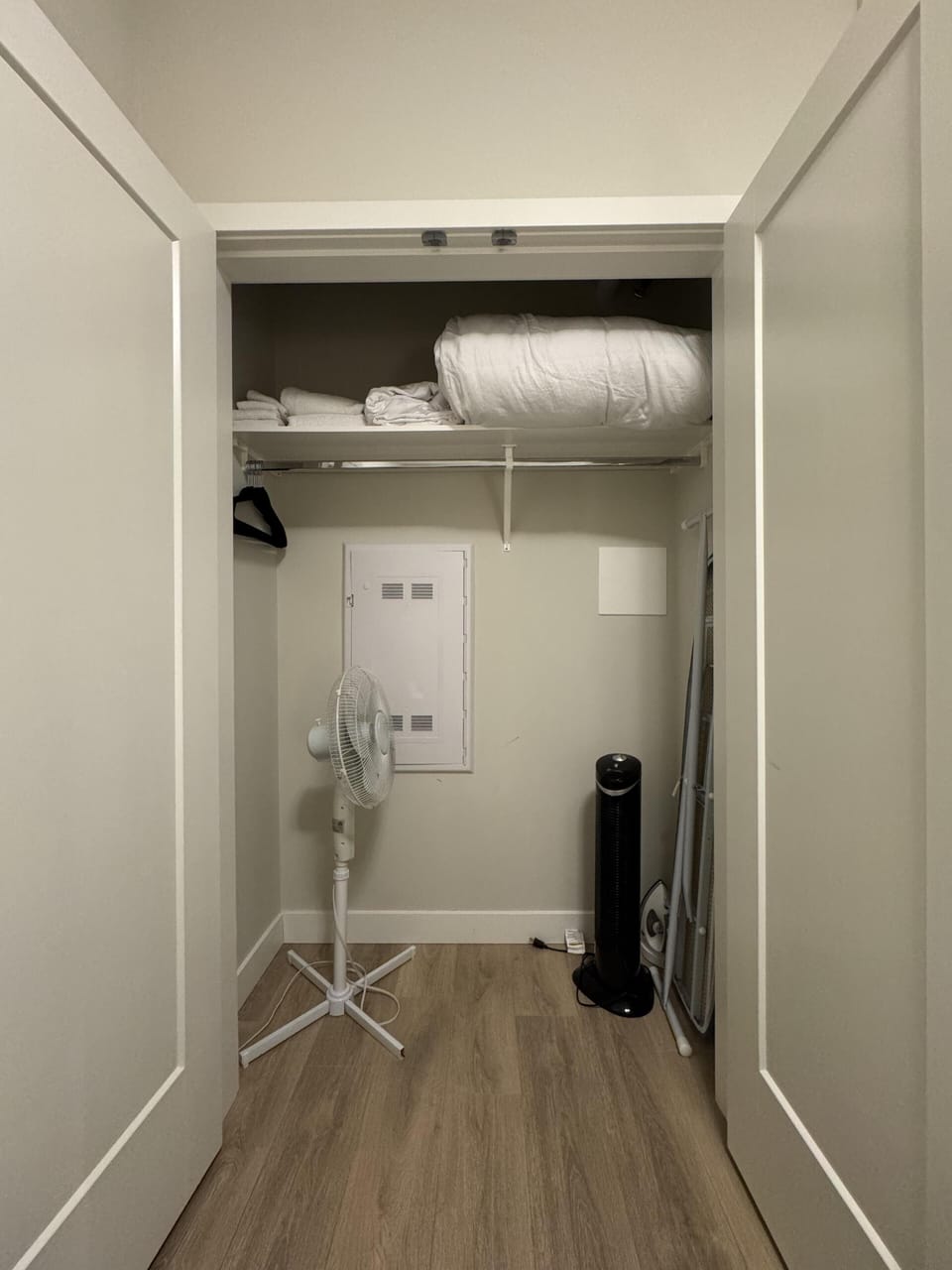 Double-door storage closet offering built-in upper shelving and hanging space for clothing and linens.