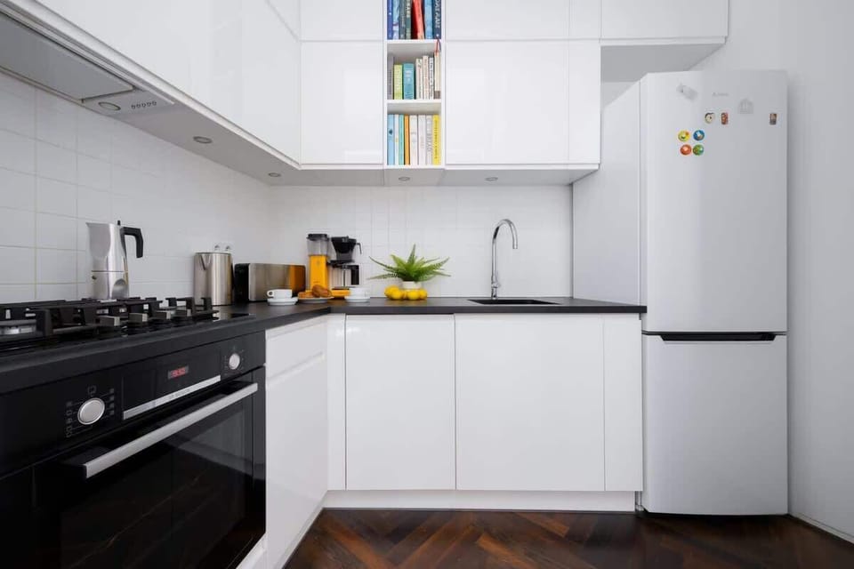  A modern kitchenette with white cabinets and a black countertop is equipped with essential appliances.