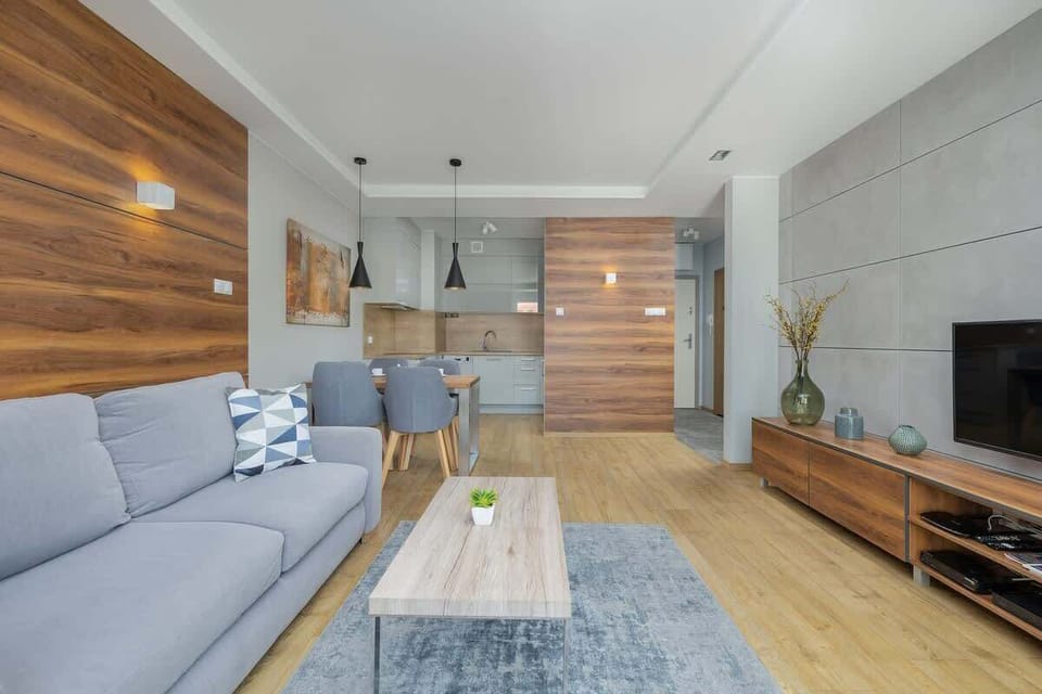 Spacious living area with gray furniture, wood paneling, and a cozy atmosphere.