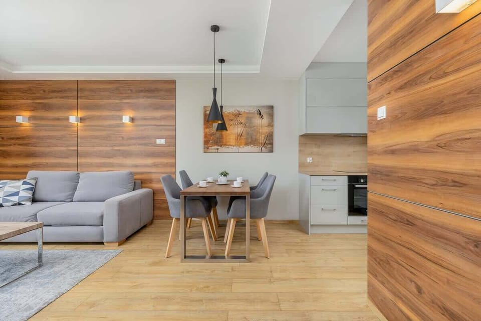 Modern living room with gray couch, wooden accent wall, and warm lighting.