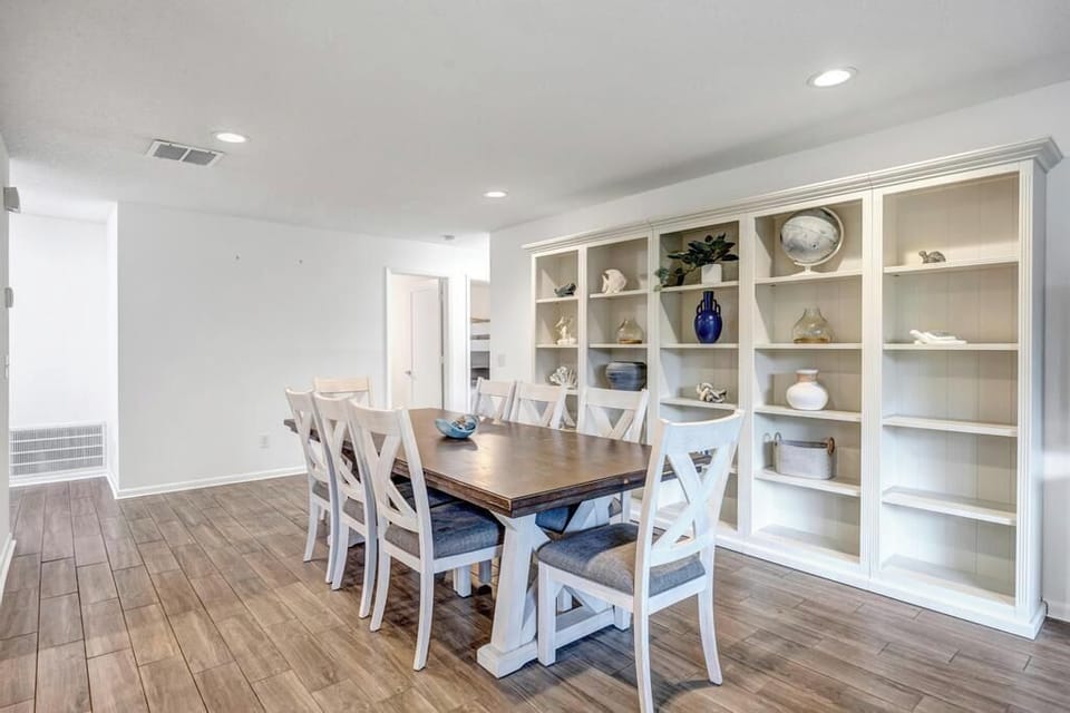 - Host dinners or work remotely at this elegant dining table with a full wall of open shelves
- Bright space with clean lines and warm wood floors feels fresh and functional
- Perfect spot for meals, games, or planning your next beach day