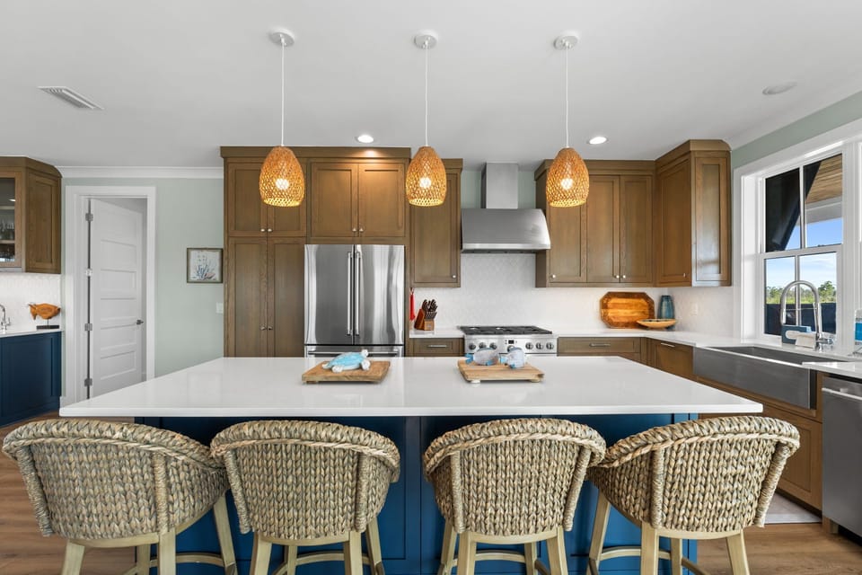 Picture yourself cooking in this spacious coastal-inspired kitchen, where woven pendant lights and natural textures create a warm, inviting atmosphere perfect for family gatherings.