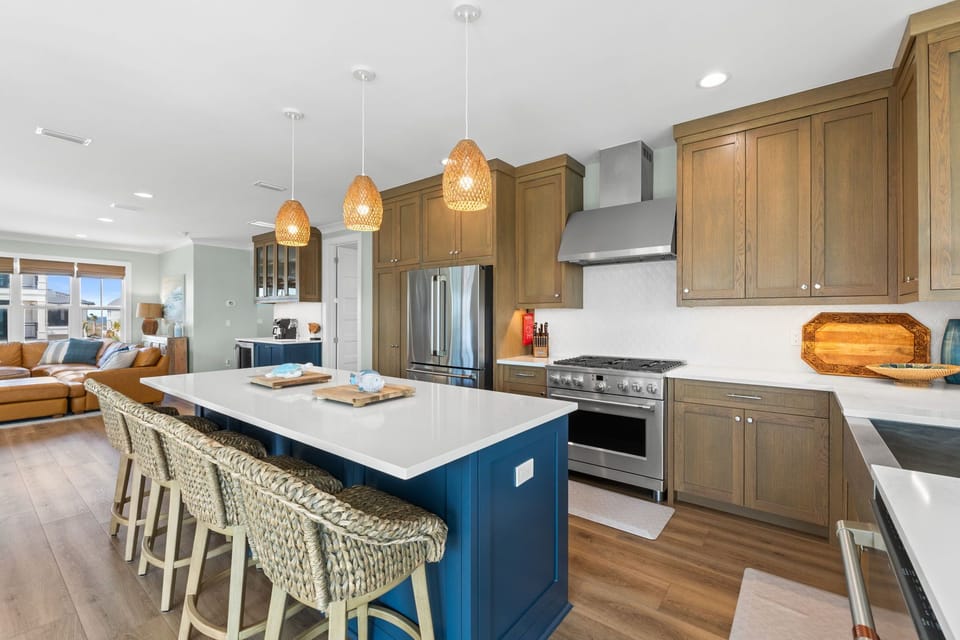Gather around your spacious island with woven pendant lights overhead, where coastal-inspired barstools invite morning coffee and meal prep becomes effortless with modern appliances and ample counter space.