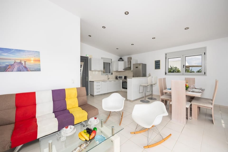 Open-plan living room with sofa, dining area, kitchen, A/C, WiFi internet, and satellite TV