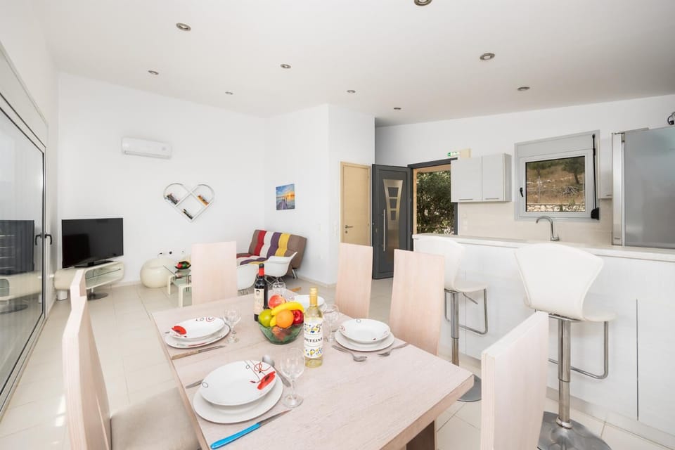 Open-plan living room with sofa, dining area, kitchen, A/C, WiFi internet, and satellite TV