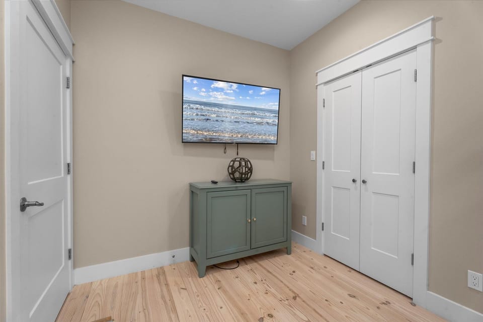 Bedroom with TV, storage space, and neutral coastal design for a relaxing stay.