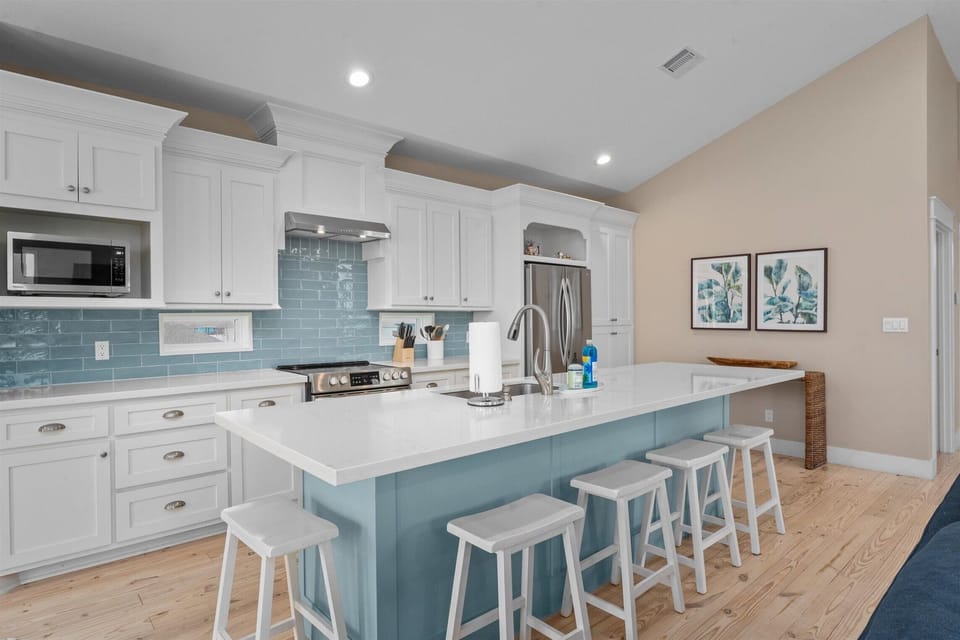 Modern kitchen with large island, bar seating, stainless steel appliances, and coastal finishes.