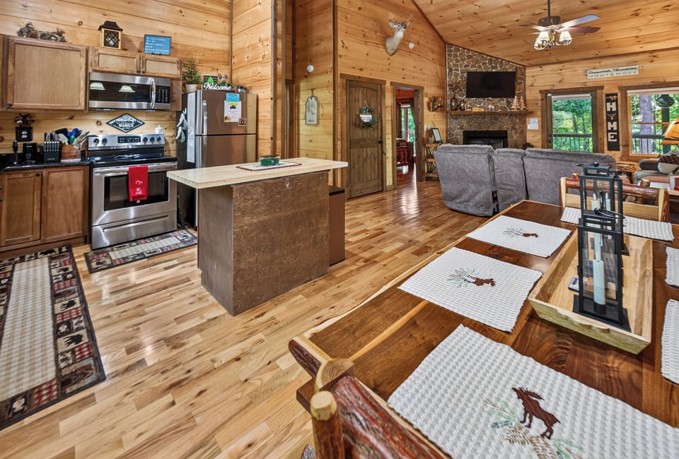 Rustic open-concept kitchen and living area with cozy fireplace and wood accents.