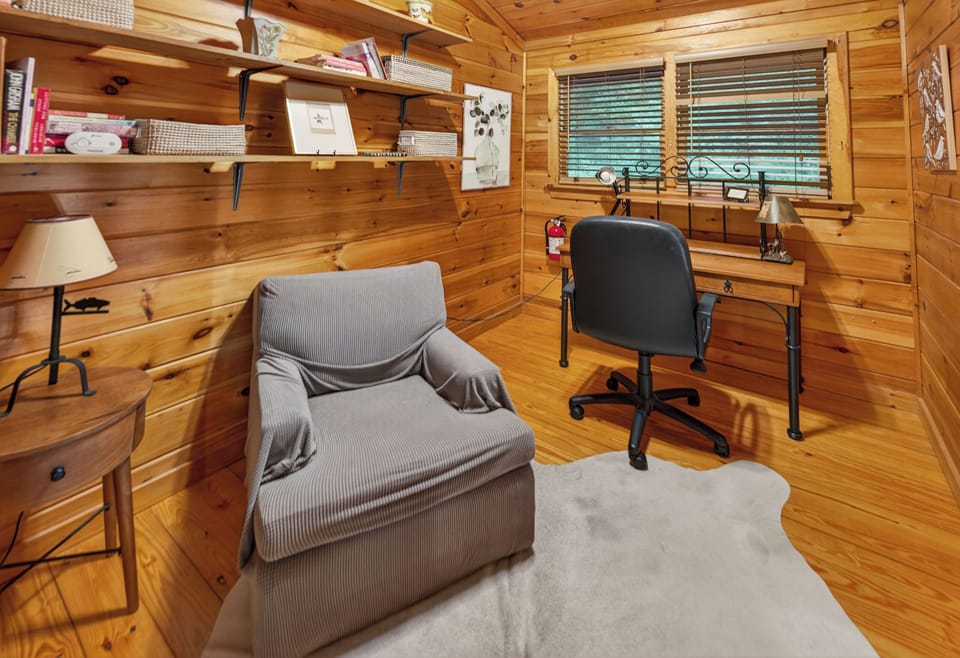 Cozy study nook with wooden walls, comfy chair, and desk for a peaceful work environment.