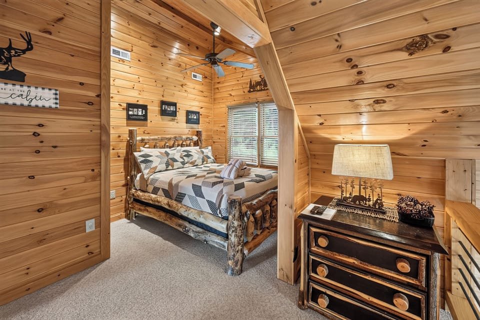 Cozy cabin bedroom with rustic log bed and warm wood paneling for a snug retreat.