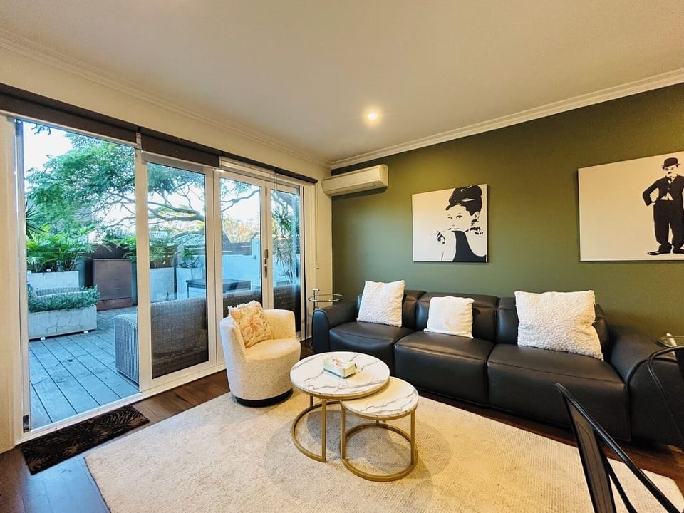 A stylish lounge space featuring a dark leather sofa and seamless transition to an outdoor area.