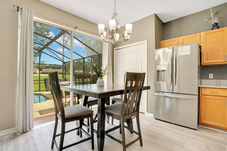 Dining area with a view of the screened pool and outdoor greenery.