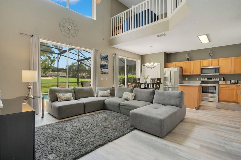 Spacious living area with modern furnishings and large windows overlooking a green outdoor space.