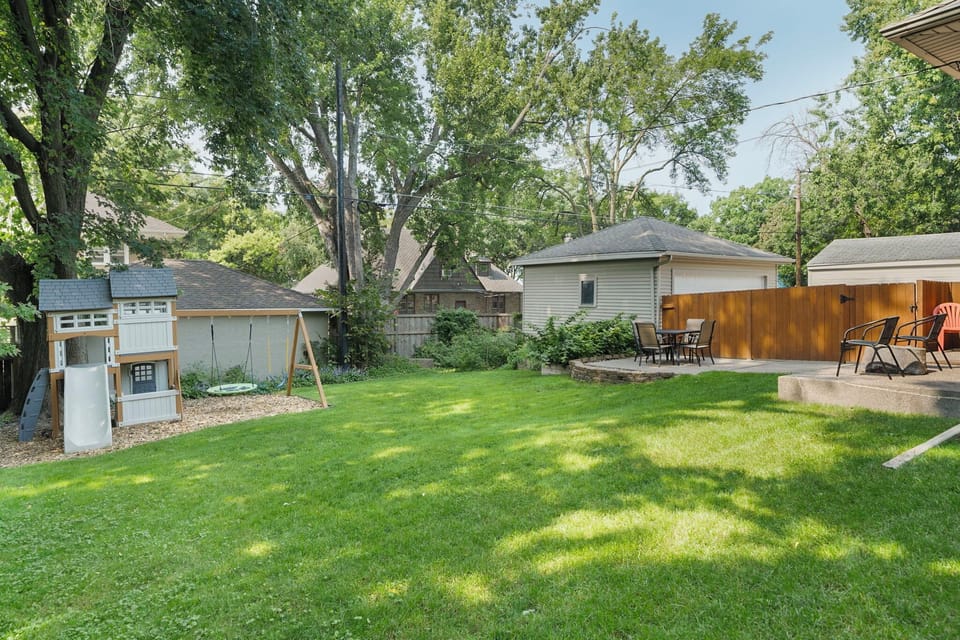 Spacious private backyard with lush green lawn, mature shade trees, and comfortable outdoor seating areas for your perfect retreat.