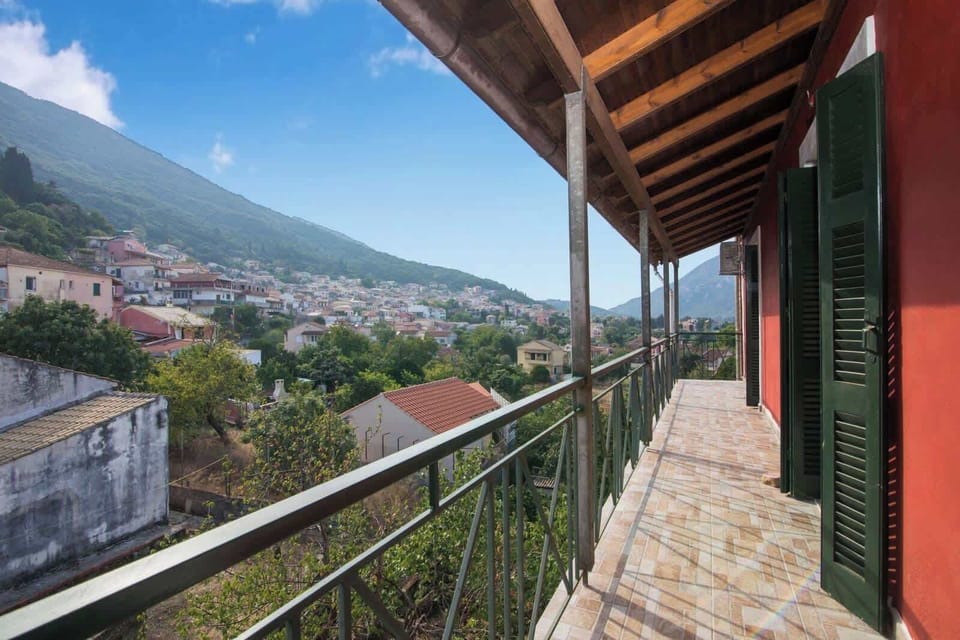Balcony View Over the Village Rooftops and Hills – A traditional Greek village panorama with mountain charm.