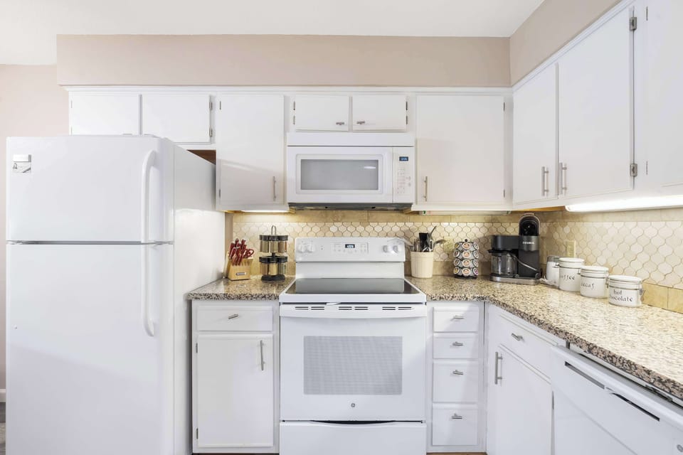 Fully equipped kitchen with electric stove, blender, and wine glasses