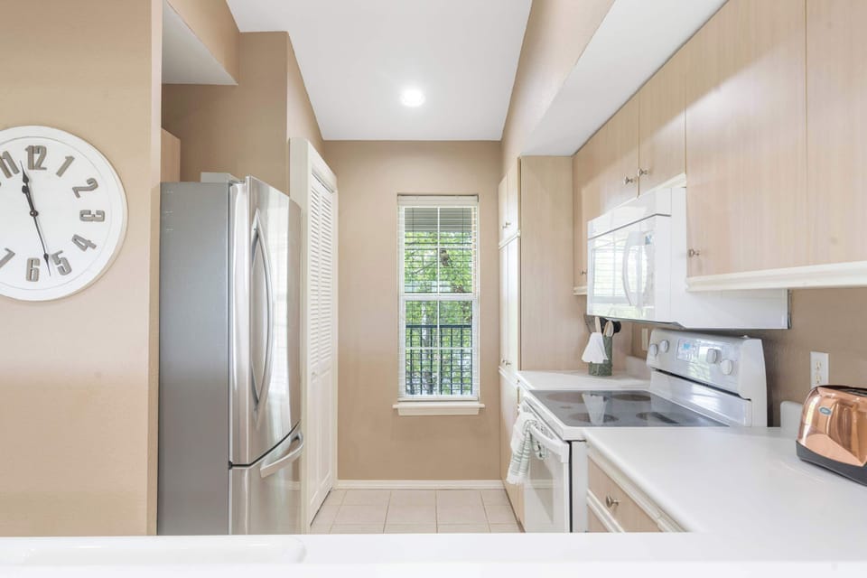 Fully equipped kitchen with stainless steel fridge and electric stove