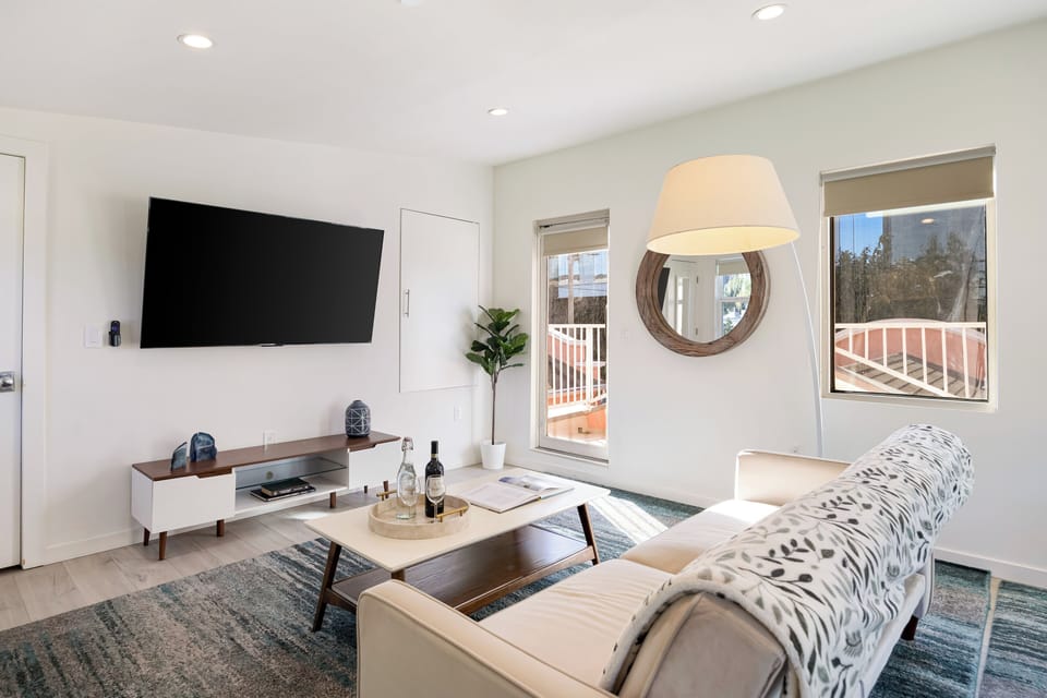 Bright, modern living area with plush seating, large smart TV, and sunlit windows—perfect for unwinding after a day out.