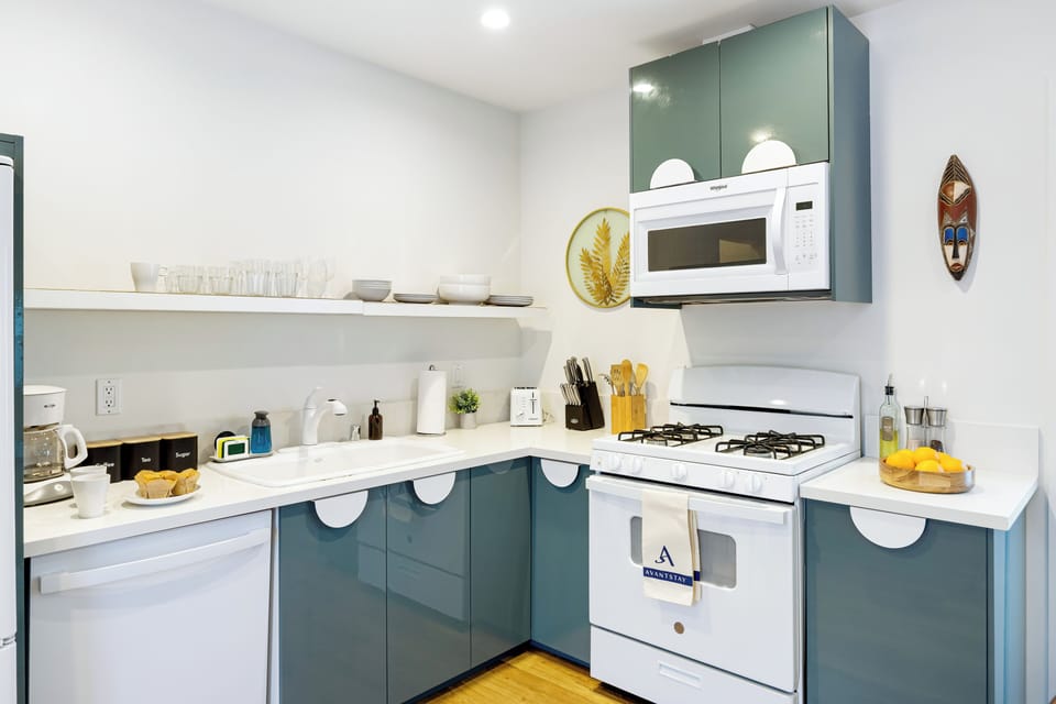 Modern, fully equipped kitchen with gas range, microwave, and stylish open shelving—perfect for easy meals and casual cooking.