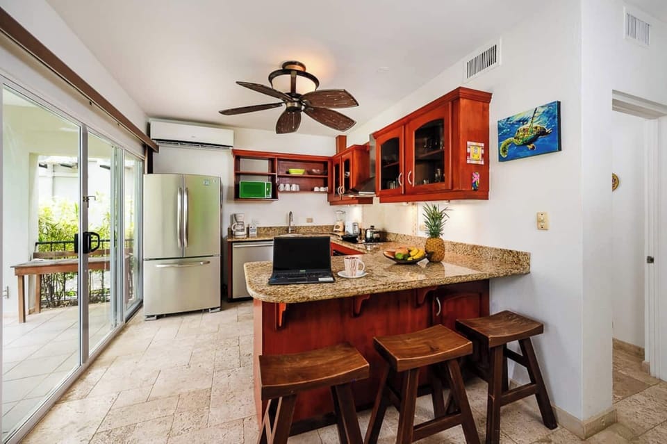 Fully equipped kitchen with balcony access, seamlessly connected to the dining area—perfect for preparing meals while enjoying tropical views in this Langosta Beach condo during your Tamarindo vacation.