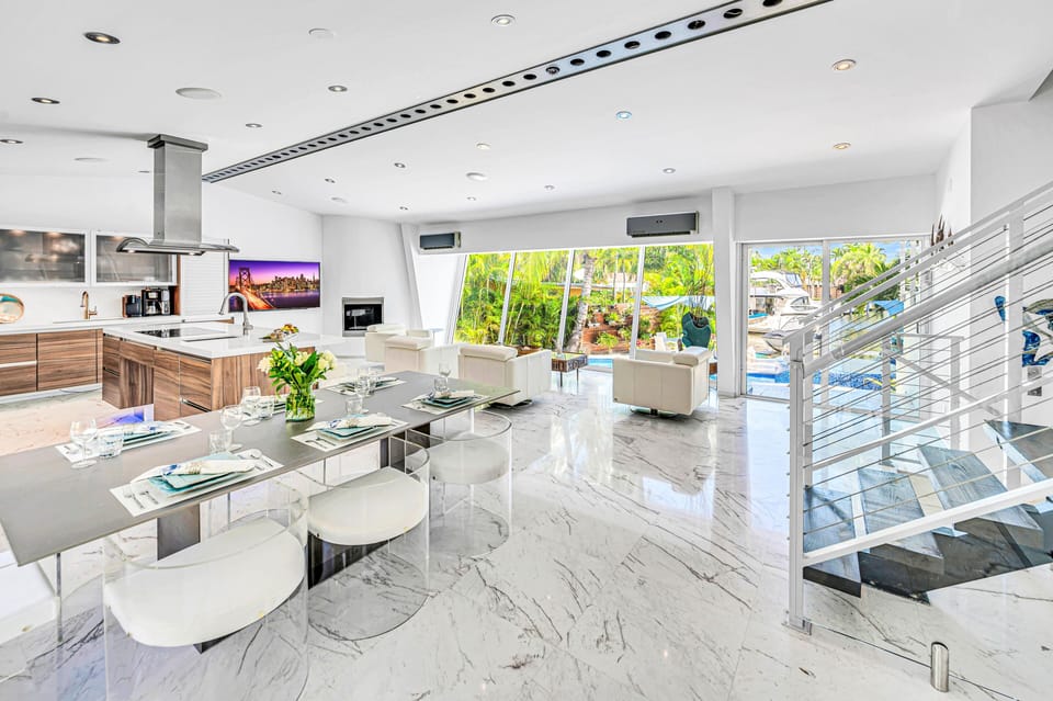 The open-concept living, dining, and chef's kitchen are bathed overlooking the tranquil canal and heated pool.