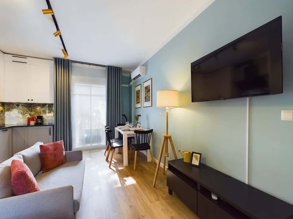  A stylish living room with a TV, large mirror, and designer lighting invites you to relax in an elegant setting.