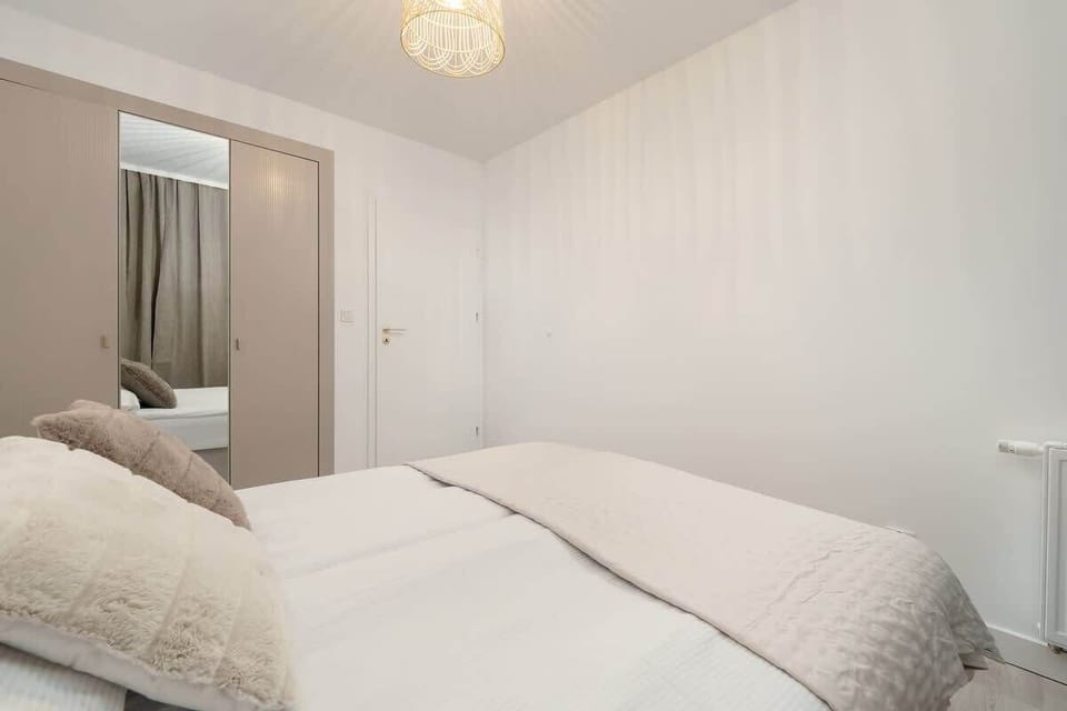 Bright and spacious bedroom with a large bed, minimalist decor, and soft lighting, creating a peaceful resting space.
