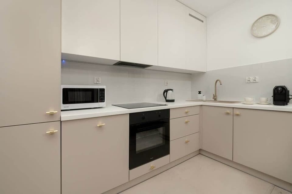 Modern kitchenette with bright cabinets and full equipment allows for preparing simple meals in comfortable conditions.