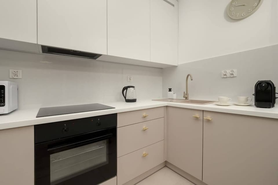Kitchenette with minimalist design, in neutral tones, equipped with a coffee machine and microwave.