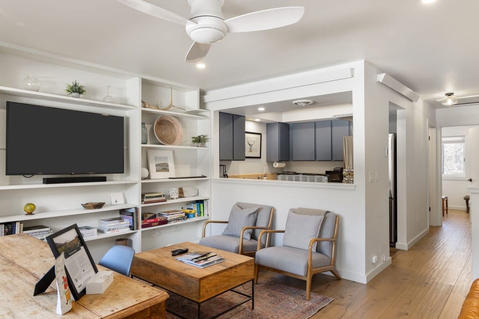 Unwind in your stylish open-concept living space with modern entertainment center and glimpse into the sleek kitchen beyond.