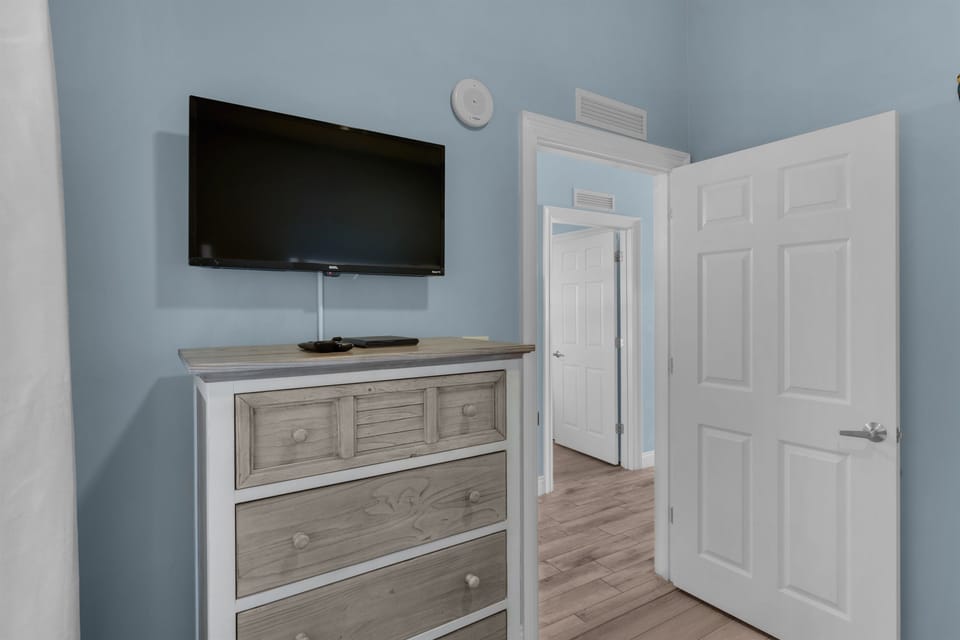 Second Bedroom -This cozy second bedroom features a comfy queen bed, TV, private bath entrance, and plenty of storage—perfect for family or friends to unwind.