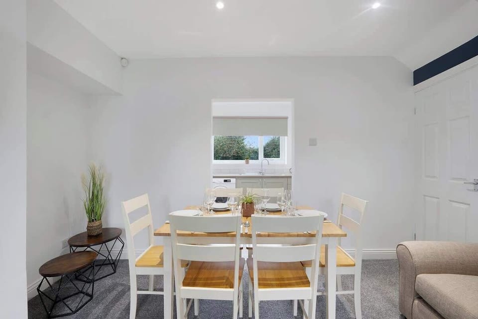The dining area, adjacent to the kitchen, features a rustic wooden table with seating for six. A stylish pendant light hangs overhead, providing a warm ambiance. Large windows let in natural light, while soft drapes add a touch of elegance. 