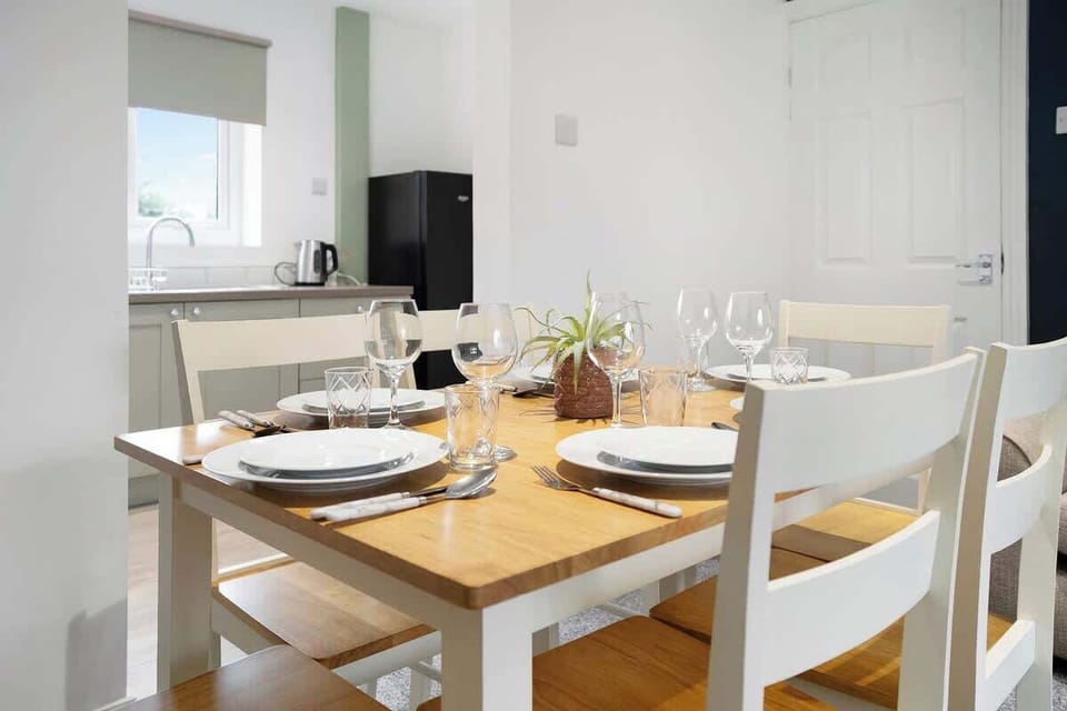 The dining area, adjacent to the kitchen, features a rustic wooden table with seating for six. A stylish pendant light hangs overhead, providing a warm ambiance. Large windows let in natural light, while soft drapes add a touch of elegance. 
