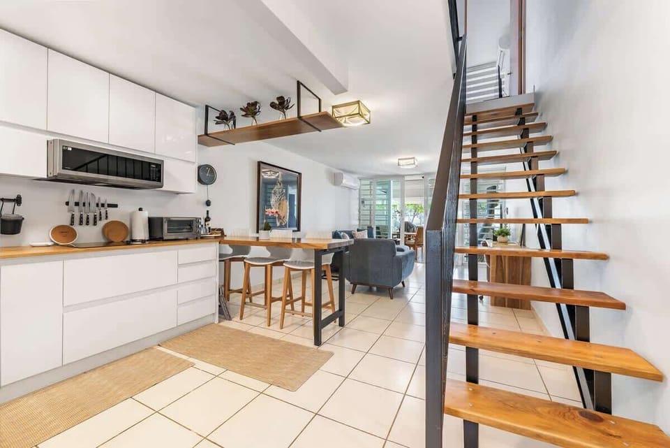 Rich natural-wood countertops, Ceiling-mounted “Floating Shelf”, Coffee Maker, Triple-door refrigerator, Flush-top stove range
Microwave Oven, Toaster Oven, Service counter with three high-back, Awonda-style barstools.