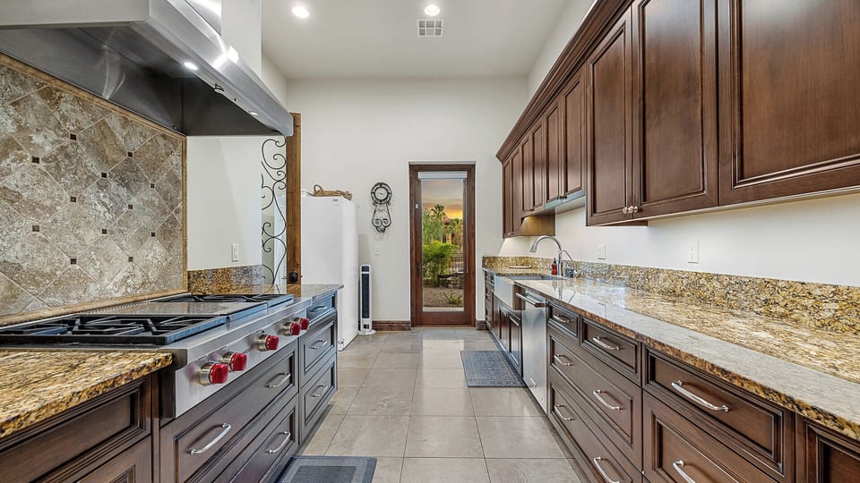 Galley kitchen with dark wood cabinets, granite counters, and outdoor views.