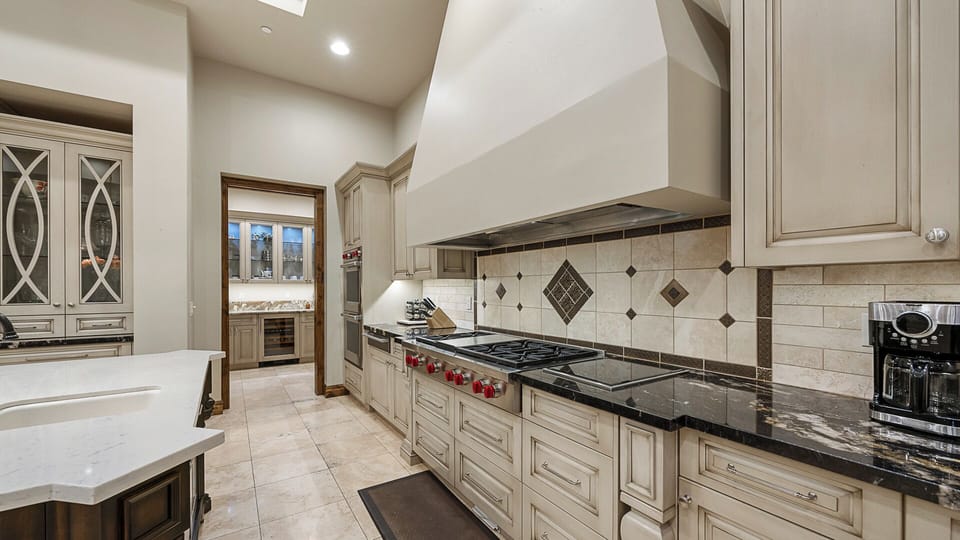 Chef’s kitchen with pro-grade range, sleek cabinetry, and dark granite counters.