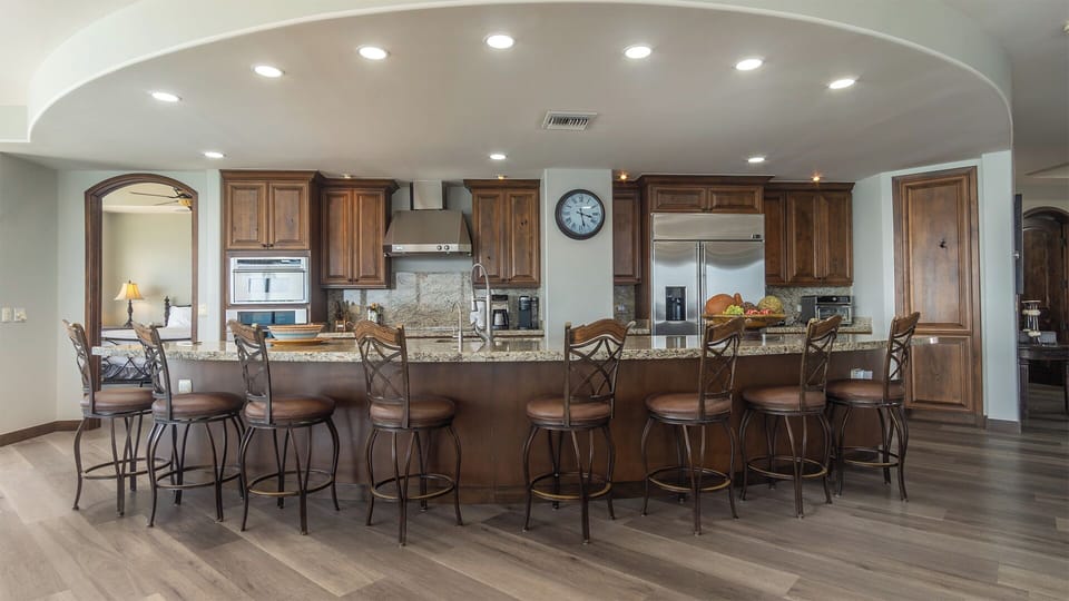 The curved counter at the kitchen island id festooned with chairs.