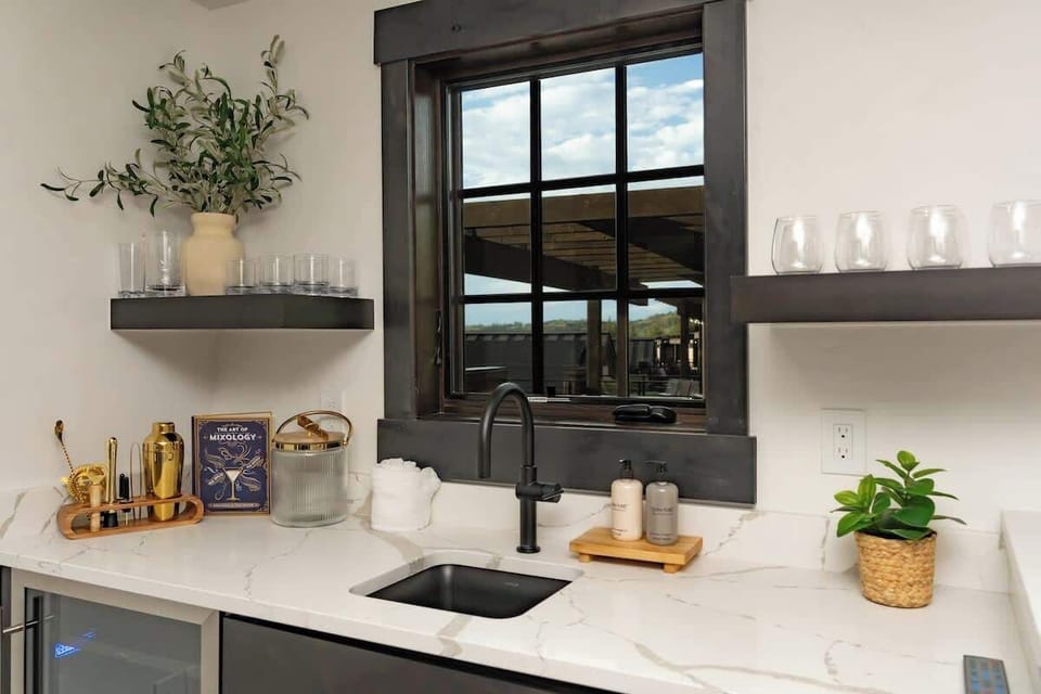 - Enjoy a drink at your private wet bar stocked with glassware and charm
- Prep cocktails or mocktails with ease while the sun pours through the window
- Open shelving and sleek finishes add modern style to every pour

