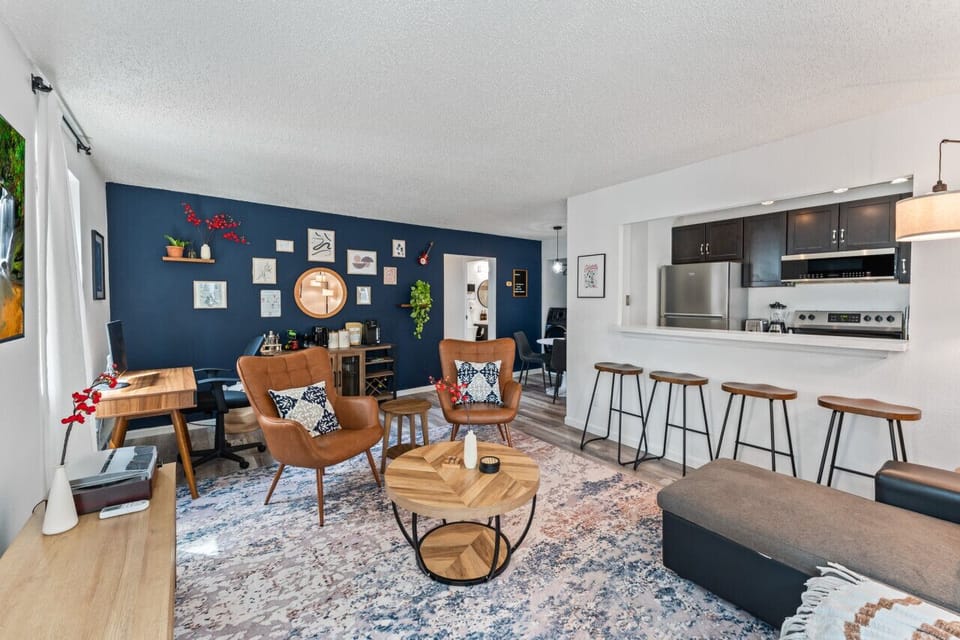 Modern, cozy living space with stylish decor, an open kitchen, and a comfy seating area. Perfect for relaxing or working, with a dedicated desk and bar seating.