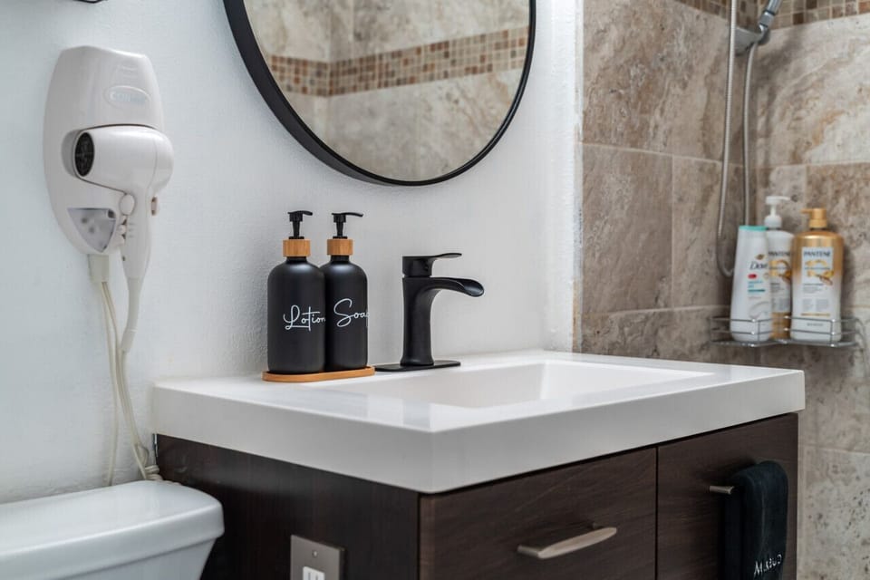 This bathroom has a nice sink, a lovely mirror, and a hair dryer with other basics.