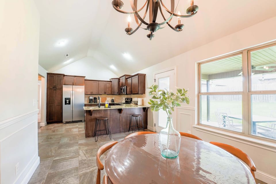 Fully equipped kitchen with modern appliances and a quaint dining area overlooking the lush backyard.