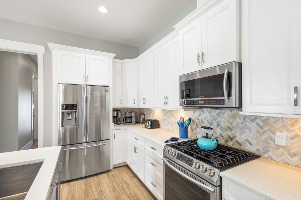 Cook your favorite meals in this bright, fully-equipped kitchen with stainless steel appliances and elegant white cabinetry.