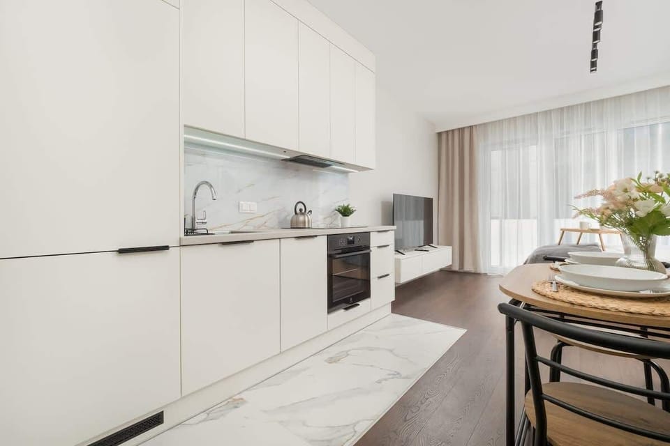 An L-shaped kitchen with sleek surfaces, built-in appliances, and a table set for two.

