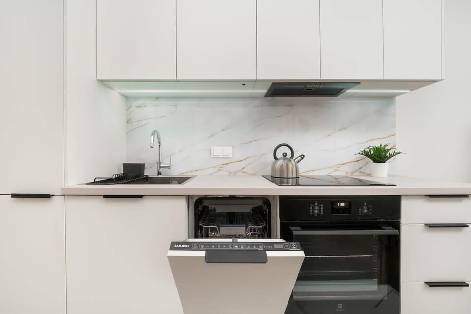 A functional kitchen with a white backsplash and cabinetry, featuring a compact layout.

