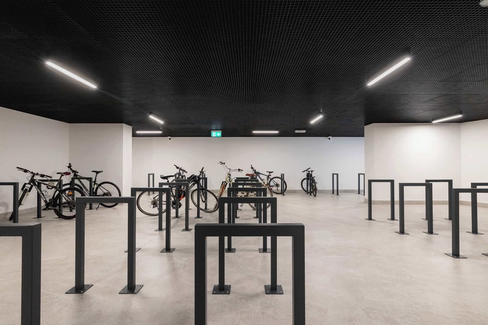 A covered bicycle parking area with a row of racks in a modern, minimalist interior.