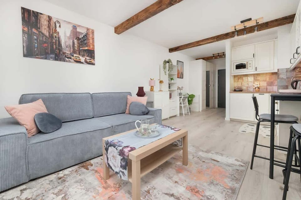 A cozy living area with a grey sofa, wood coffee table, and breakfast bar.

