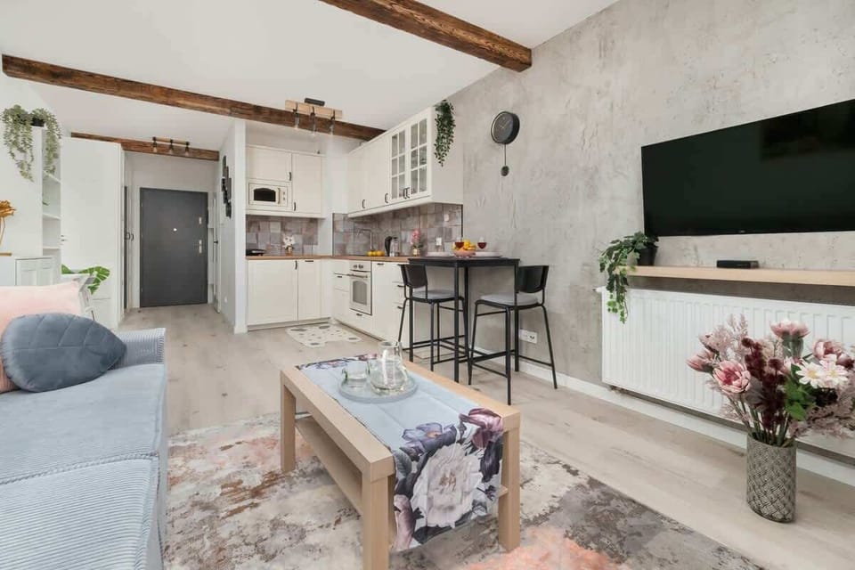 A television mounted on the wall with a kitchen and breakfast bar in view.

